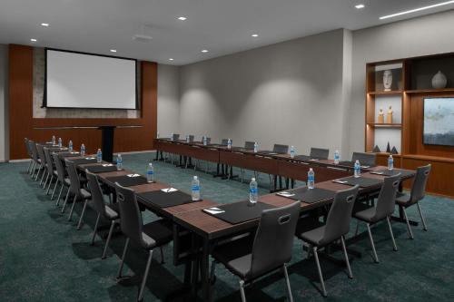 a conference room with tables and chairs and a screen at AC Hotel by Marriott Raleigh North Hills in Raleigh
