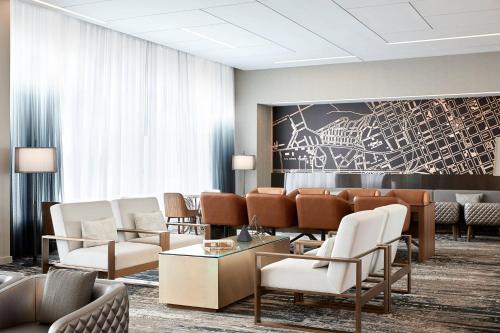a waiting room with chairs and tables and a painting at AC Hotel by Marriott Raleigh North Hills in Raleigh