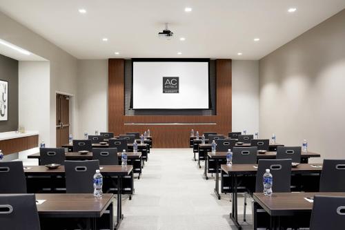 a lecture room with tables and a projection screen at AC Hotel by Marriott Raleigh North Hills in Raleigh