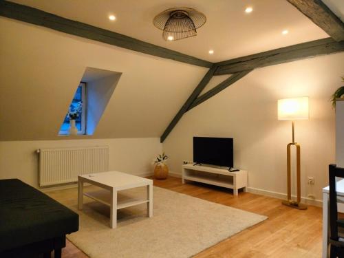 a living room with a flat screen tv and a table at Home Sweet Home WiFi, TV Access, Strasbourg 25min in Wasselonne