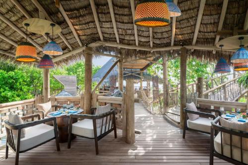 a restaurant with tables and chairs on a wooden deck at JW Marriott Maldives Resort & Spa in Funadhoo