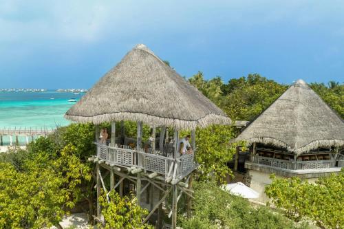 two resorts with straw umbrellas on the beach at JW Marriott Maldives Resort & Spa in Funadhoo