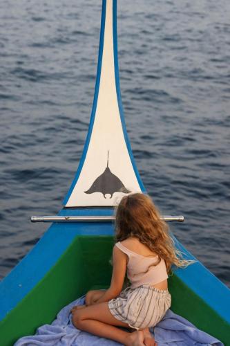a little girl sitting on a boat with a toy sail at JW Marriott Maldives Resort & Spa in Funadhoo