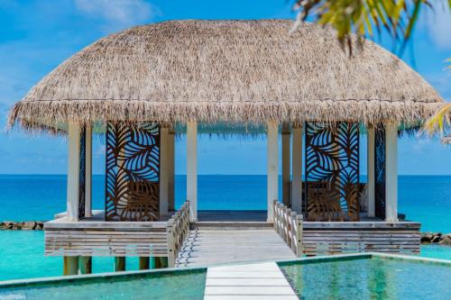 a resort with a swimming pool and a straw hut at JW Marriott Maldives Resort & Spa in Funadhoo
