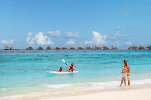 a man in a kayak in the water on a beach at JW Marriott Maldives Resort & Spa in Funadhoo