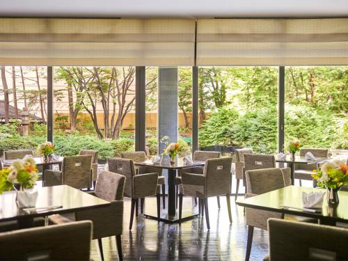 a restaurant with tables and chairs and large windows at Sapporo Grand Hotel in Sapporo