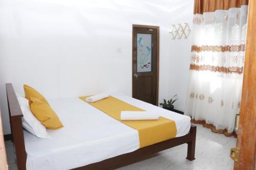 a bedroom with a bed with white sheets and yellow pillows at Dinu Senu Dream Guest in Midigama