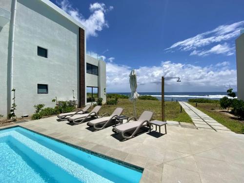 a group of lounge chairs sitting next to a swimming pool at Beachfront Luxury 3 Bedrooms Apartment in Poste Lafayette