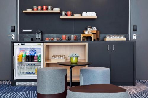 a bar with two stools and a refrigerator with drinks at Courtyard by Marriott Oberpfaffenhofen Munich South in Gilching