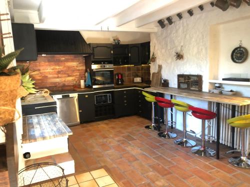 - une cuisine avec tabourets de bar rouges et jaunes dans l'établissement Superbe bergerie en cœur de foret avec piscine privée lac rivière cascades, à Carcès