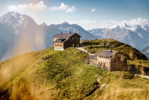 a house on a hill with mountains in the background at Luxury Naturperle Haus Alpenprinzessin helles Holzhaus zentral , modern & großräumig in Neustift im Stubaital