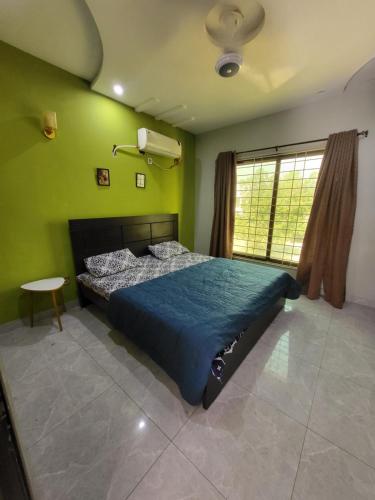 a bedroom with a blue bed in a green wall at Beautiful villa in bahria town karachi in Karachi