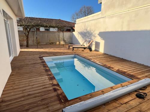 居让梅斯特拉Maison familiale piscine 3 chambres Gujan-Mestras !的一个带木甲板和长凳的游泳池
