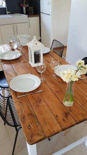 - une table en bois avec des assiettes, des verres et des fleurs dans l'établissement Kalon Bihan Gîte, à Poullaouen
