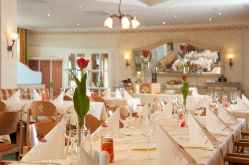 a dining room with white tables with a red flower on it at Hotel Althof Retz in Retz