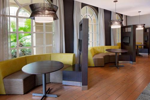 a lobby with yellow chairs and tables and windows at Courtyard by Marriott Fort Lauderdale North/Cypress Creek in Fort Lauderdale