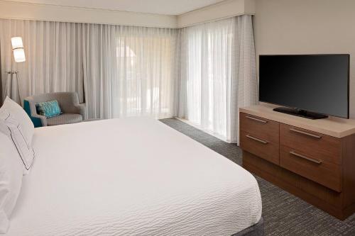 a hotel room with a bed and a flat screen tv at Courtyard by Marriott Fort Lauderdale North/Cypress Creek in Fort Lauderdale