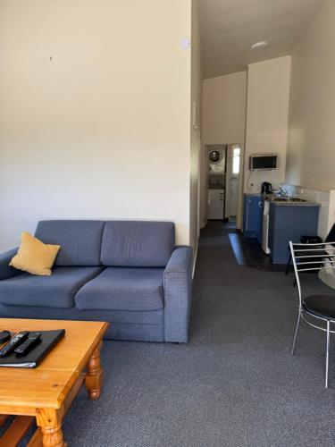 a living room with a blue couch and a table at Bay Road Motels in Haast