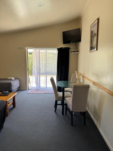 a room with a table and chairs and a bedroom at Bay Road Motels in Haast