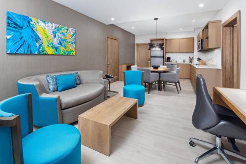a living room with a couch and chairs and a kitchen at Courtyard by Marriott Port of Spain in Port-of-Spain