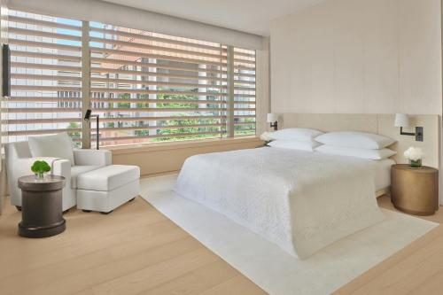 a bedroom with a white bed and a large window at The Singapore EDITION in Singapore