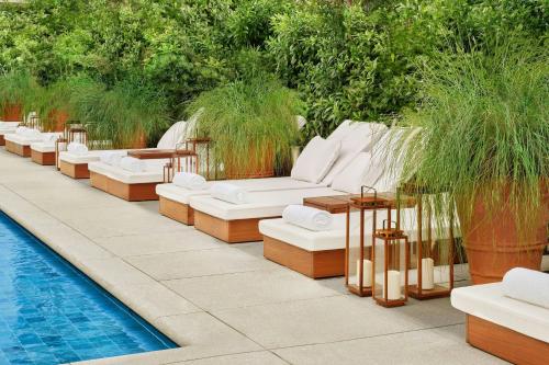 a row of white couches sitting next to a pool at The Singapore EDITION in Singapore