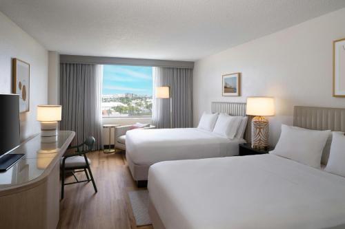 a hotel room with two beds and a desk at Renaissance Fort Lauderdale Cruise Port Hotel in Fort Lauderdale