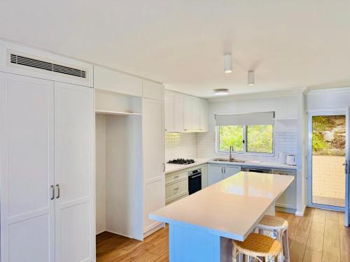 a kitchen with white cabinets and a counter top at Perfect Oceanfront Cottesloe apartment in Perth