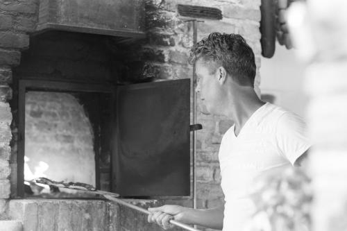 Un uomo sta mettendo il cibo in un forno di Casa Tartufo a Doglio