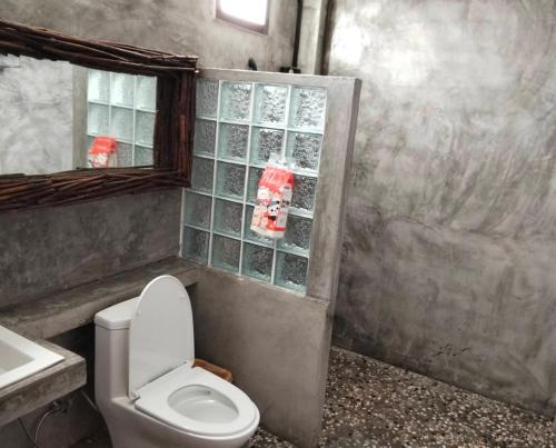 a bathroom with a toilet and a sink and a mirror at เรือนบรรเจิดโฮมสเตย์ in Ban Nok
