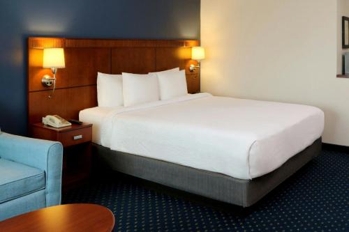 a hotel room with a large bed and a chair at Courtyard Monterrey San Jeronimo in Monterrey