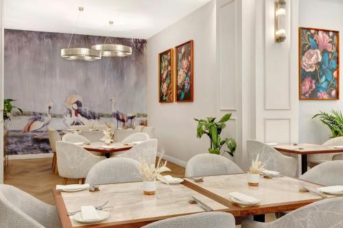 a restaurant with tables and chairs and paintings on the wall at African Pride Melrose Arch, Autograph Collection in Johannesburg