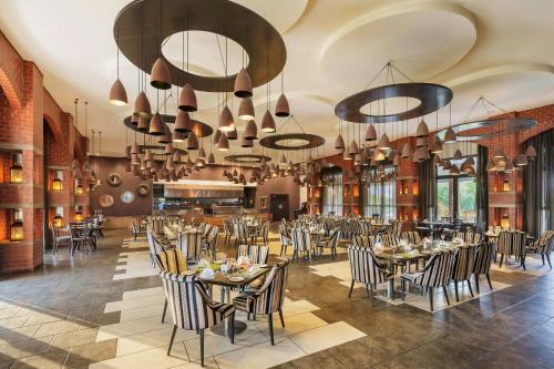 a dining room with tables and chairs and chandeliers at Protea Hotel by Marriott Ndola in Ndola
