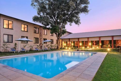 a hotel with a swimming pool in front of a building at Protea Hotel by Marriott Ndola in Ndola