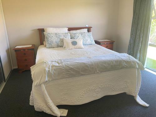 Un dormitorio con una gran cama blanca con almohadas. en Rolleston New Zealand, en Rolleston