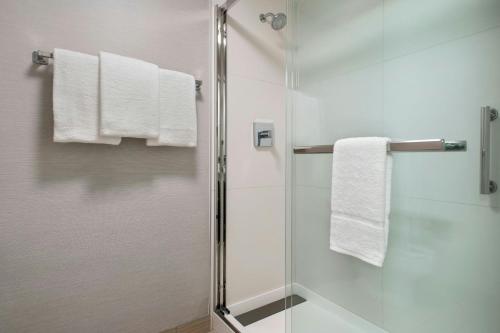 a bathroom with a shower with white towels at Courtyard by Marriott Rye in Rye