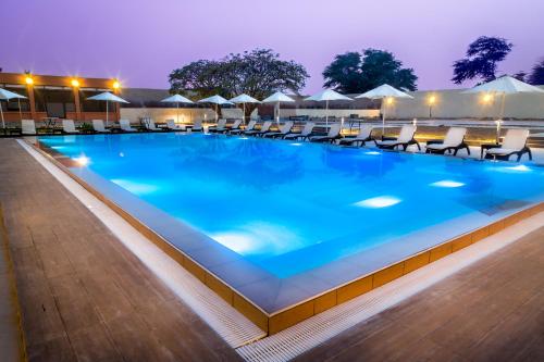 a swimming pool at night with chairs and umbrellas at Azalaï Hôtel Nouakchott in Nouakchott