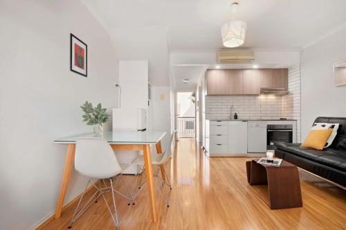 a kitchen and living room with a table and a couch at Melbourne Street Haven in North Adelaide