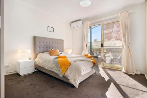 a white bedroom with a bed and a large window at Melbourne Street Haven in North Adelaide