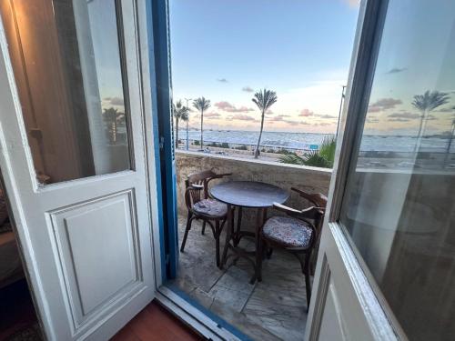 a balcony with a table and chairs and the ocean at Alexandria private rooms, Only For Men 仅限男士 in Alexandria