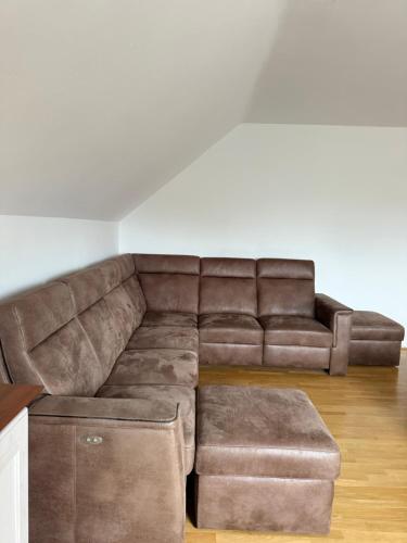 a living room with a brown couch and a stool at Dům FAUNA V Českosaském Švýcarsku in Janov
