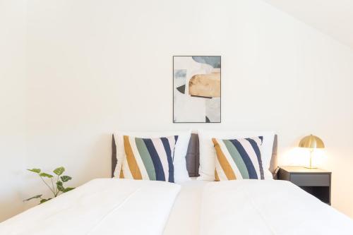 a bedroom with a white bed with striped pillows at living TIMELESS - Adler Apartments Sasbachwalden in Sasbachwalden