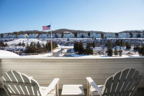 two white chairs sitting on a balcony with a view of a city at Inn at Bay Harbor, Autograph Collection in Petoskey