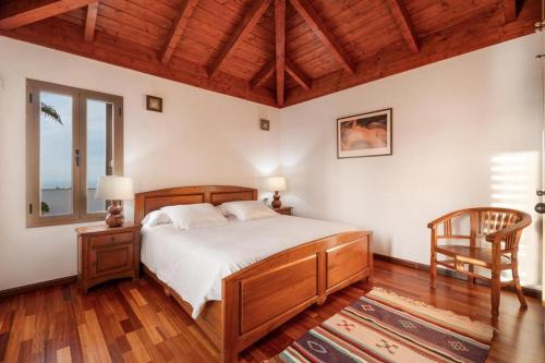 a bedroom with a bed and a chair and a window at Casa Tagoro, facing the Ocean in Tacoronte
