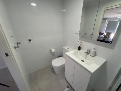 a white bathroom with a toilet and a sink at A newly renovated home and only 2 minutes to Highway - modern and handy in Raymond Terrace