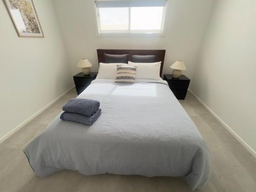 a bedroom with a large bed with two pillows on it at A newly renovated home and only 2 minutes to Highway - modern and handy in Raymond Terrace