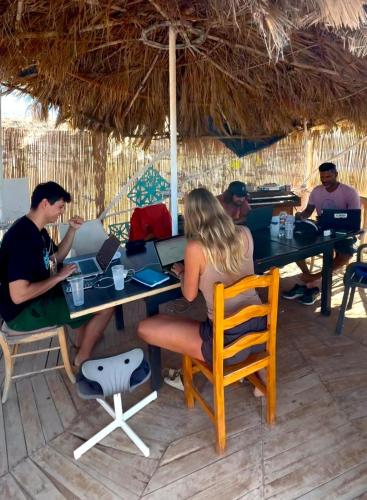 a group of people sitting at a table with laptops at Adeje - TwinFin Hostel & Surf Yoga Camp in Callao Salvaje