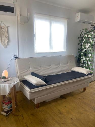 a white couch in a room with a window at cabaña NFF in Punta Del Diablo