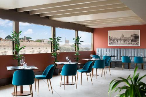 ein Restaurant mit Tischen und Stühlen und großen Fenstern in der Unterkunft Sina Bernini Bristol, Autograph Collection in Rom