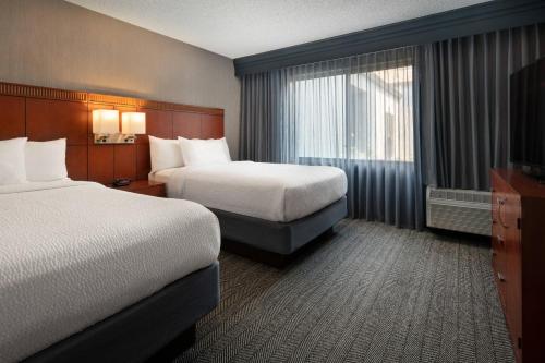 a hotel room with two beds and a television at Courtyard by Marriott Fresno in Fresno